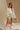 Full body view of female model wearing the Kimberly Cream Pleated Long Sleeve Top which features Cream Sheer Plisse Fabric, Cropped Waist, Lettuce Hem Details, Round Neckline and Open Back with Tie Closures