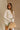 Front view of female model wearing the Kimberly Cream Pleated Long Sleeve Top which features Cream Sheer Plisse Fabric, Cropped Waist, Lettuce Hem Details, Round Neckline and Open Back with Tie Closures