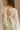 Back view of female model wearing the Kimberly Cream Pleated Long Sleeve Top which features Cream Sheer Plisse Fabric, Cropped Waist, Lettuce Hem Details, Round Neckline and Open Back with Tie Closures