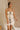Front view of model sitting while wearing the Rosalind Cream & Black Sheer Tank that has cream sheer fabric, cream lining, black straps, and black tie and ruffle trim details. Worn with matching skirt.