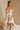 Front view of model wearing the Rosalind Cream & Black Sheer Mini Skirt, which has lined cream sheer fabric, black ruffle and tie details, and an elastic waist. Paired with matching top.