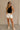 Full body front view of model wearing the Rayna Black Ribbed Tank, that features wide ribbed fabric, a round neckline, and sleeveless body. Worn with white shotrs.