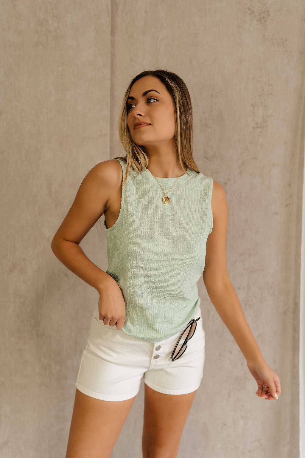 Front view of female model wearing the Kimber Mint Textured Tank that features mint green textured fabric, sleeveless body, and round neck. Tank is untucked