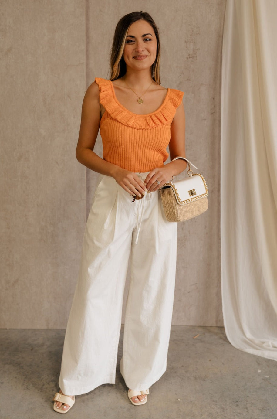 Full body view of female model wearing the Lillian Orange Ruffle Tank which featuresOrange Knit Fabric, Scooped Neckline, Ruffle Details and Sleeveless.