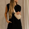 Front view of female model wearing the Rayven Black Sleeveless Mini Dress which features black cotton fabric, mini length, ribbed hem, small side slits, two side slit pockets, a round neckline, and sleeveless.