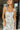 Front view of female model wearing the Felicity White and Blue Floral Maxi Ruffle Dress which features Blue and Green Floral Design, Maxi Length, White Lining, Slit on the side with ruffle details, Square Neckline, Adjustable ruffles straps and Back zipper with hook closure.