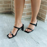 Right front angle view of female model wearing  the Yaya Dress Sandal in Black which features black patent leather fabric, square toe, two straps, slide-on style and 3 inch heel.