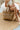 Front view of female model wearing the Beach Please Pearl Woven Tote which features tan rattan woven fabric, "Beach Please" is delicately crafted in pearls on the front and two straps.