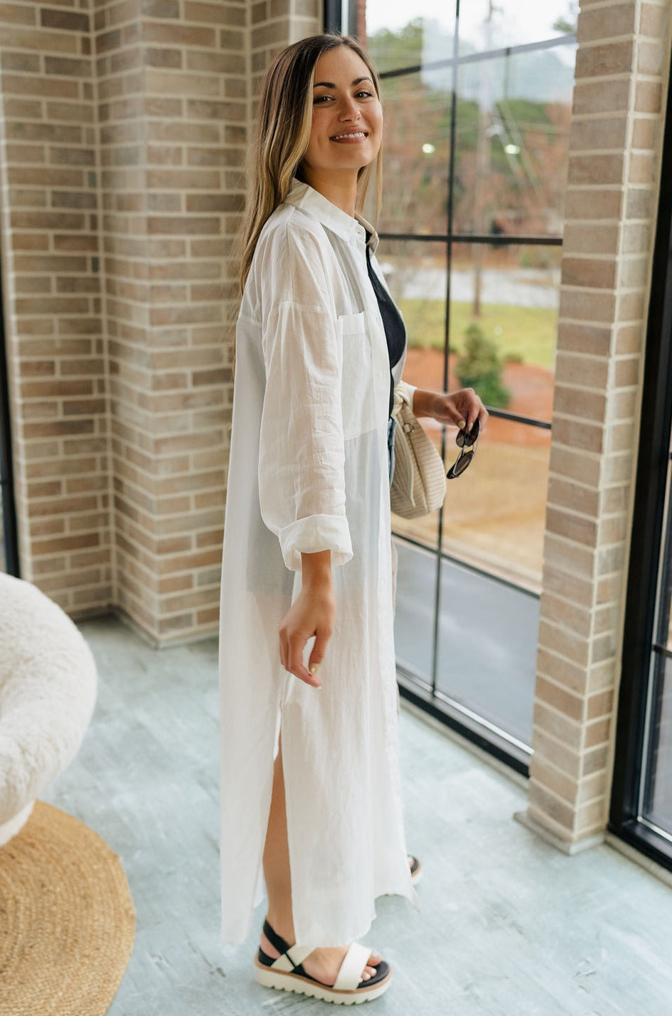  Full body side view of female model wearing the Luna Off White Button-Up Cover Up Dress which features White Cotton Fabric, Midi Length, Slits on each side , Button-Up Front Closure, Collared Neckline and Long Sleeves.