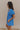 Side view of model wearing the Marissa Blue and White Floral Short Sleeve Romper which features Blue Lightweight Fabric, White Floral Design, Blue Lining, Square Neckline, Short Puff Sleeves and Smocked Back.