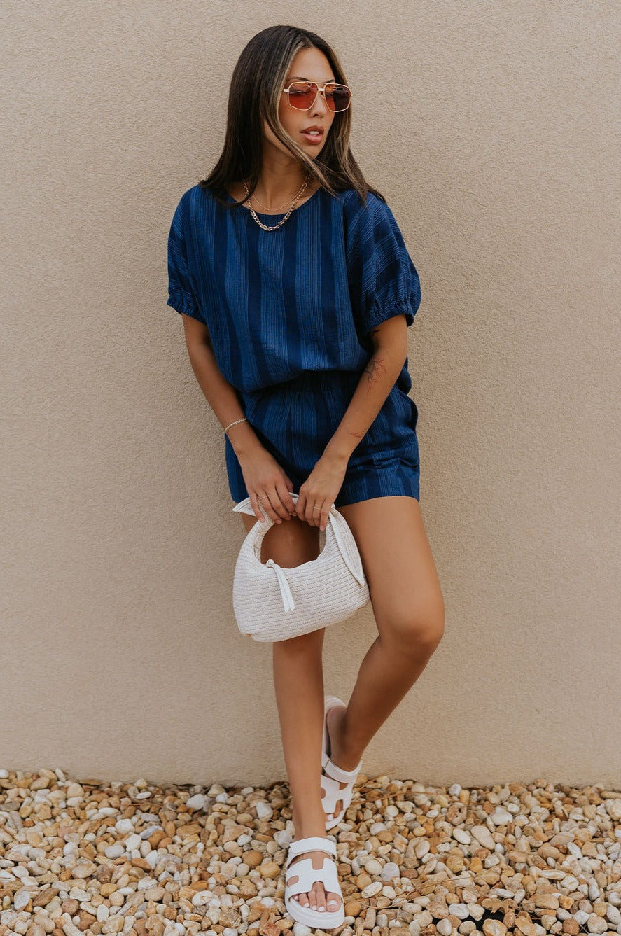 Full body view of female model wearing the Julissa Navy Stripe Shorts which features Navy Blue with Light Blue Stripe Design, Elastic Waistband, Two Front Pockets and Two Back Pockets.