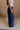 Side view of female model wearing the Olivia Navy Blue Smocked Pants which features Navy Knit Fabric, Wide Pant Legs, Navy Lining and Smocked Waistband