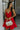 front view of model wearing the Loretta Red Sleeveless Mini Dress that has a tiered skirt, surplice neckline, and thin straps. Worn with white purse.