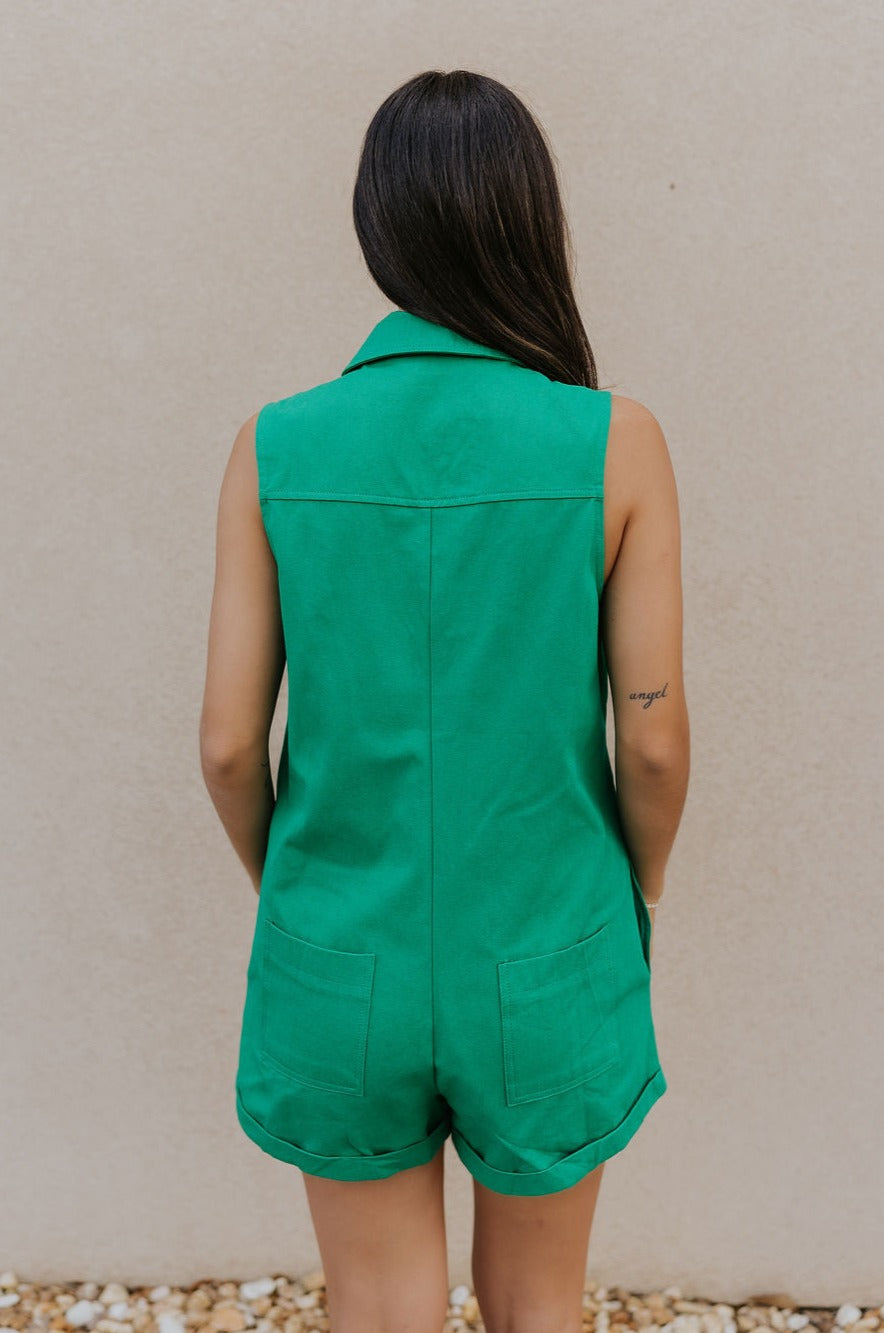 Back view of female model wearing the Serena Zip-Up Sleeveless Romper in Green which features Cotton Fabric, Two Front Pockets, Two Back Pockets, Front Zip-Up Closure, Collared Neckline and Sleeveless.