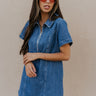 Front view of model wearing the Jada Denim Short Sleeve Mini Dress that has dark wash denim fabric, a zippered neckline with a collar, and short sleeves.