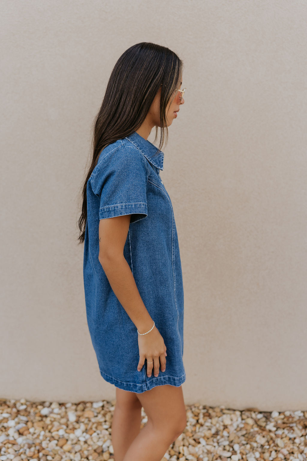 Right side view of model wearing the Jada Denim Short Sleeve Mini Dress that has dark wash denim fabric, a zippered neckline with a collar, and short sleeves.