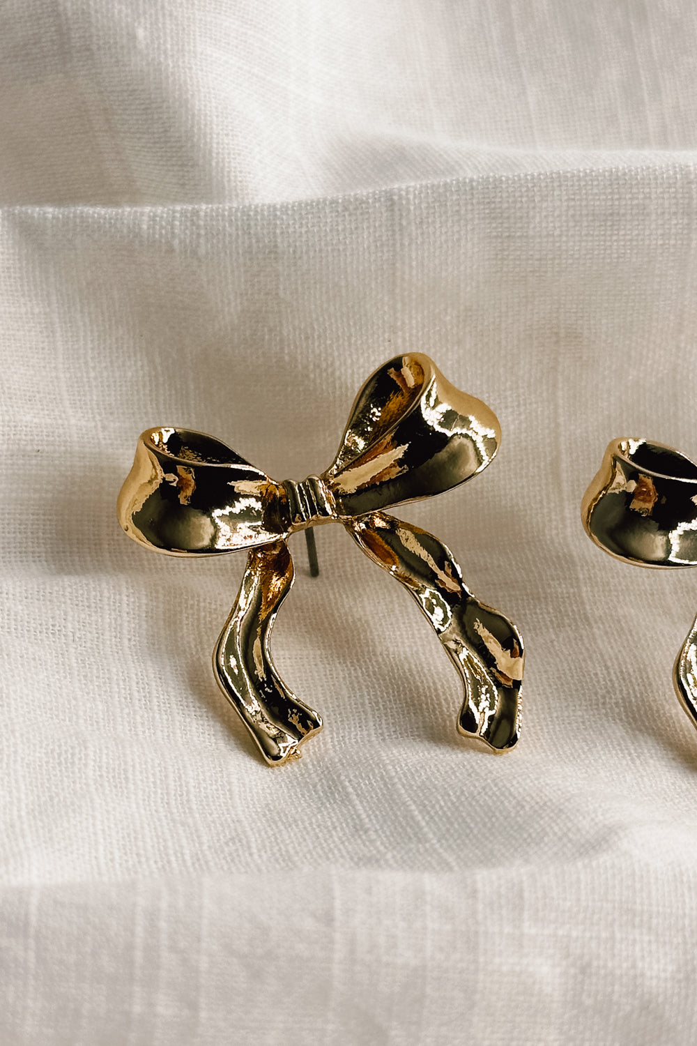 Close up view of the Lois Gold Bow Stud Earrings which features gold bow shaped earrings with stud back closures