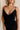 Close up view of female model wearing the Sophia Black Plunge Neckline Mini Dress which features Black Lightweight Fabric, Mini Length, Side Ruched Detail with Covered Buttons Closure, Scoop Neckline, Adjustable Straps and Sleeveless