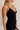 Close up side view of female model wearing the Sophia Black Plunge Neckline Mini Dress which features Black Lightweight Fabric, Mini Length, Side Ruched Detail with Covered Buttons Closure, Scoop Neckline, Adjustable Straps and Sleeveless