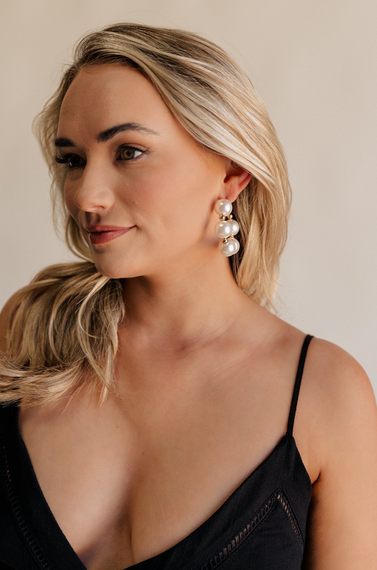 oversized pearl beads with gold details and large open hoops with back closureSide view of female model wearing the Delilah Pearl Hoop Earring which features oversized pearl beads with gold details and large open hoops with back closure