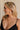 Side view of female model wearing the Delilah Pearl Hoop Earring which features oversized pearl beads with gold details and large open hoops with back closure