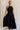Full body view of female model wearing the Luna Halter Tie Tiered Maxi Dress in black which features Lightweight Fabric, Tiered Body, Maxi Length, Thigh Length Lining, Halter Neckline with Tie and Open Back