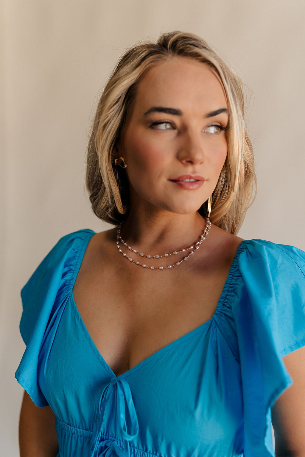 Front view of female model wearing the Emma Pearl & Gold Double Layer Necklace which features pearl and gold beads linked together in two layers and adjustable clasp closure.