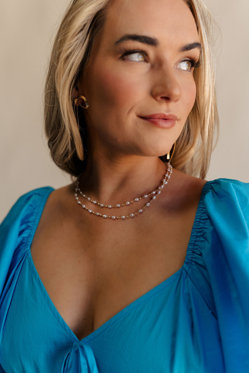 Close up front view of female model wearing the Emma Pearl & Gold Double Layer Necklace which features pearl and gold beads linked together in two layers and adjustable clasp closure.