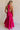  Full body back view of female model wearing the Luna Halter Tie Tiered Maxi Dress in Pink which features Lightweight Fabric, Tiered Body, Maxi Length, Thigh Length Lining, Halter Neckline with Tie and Open Back