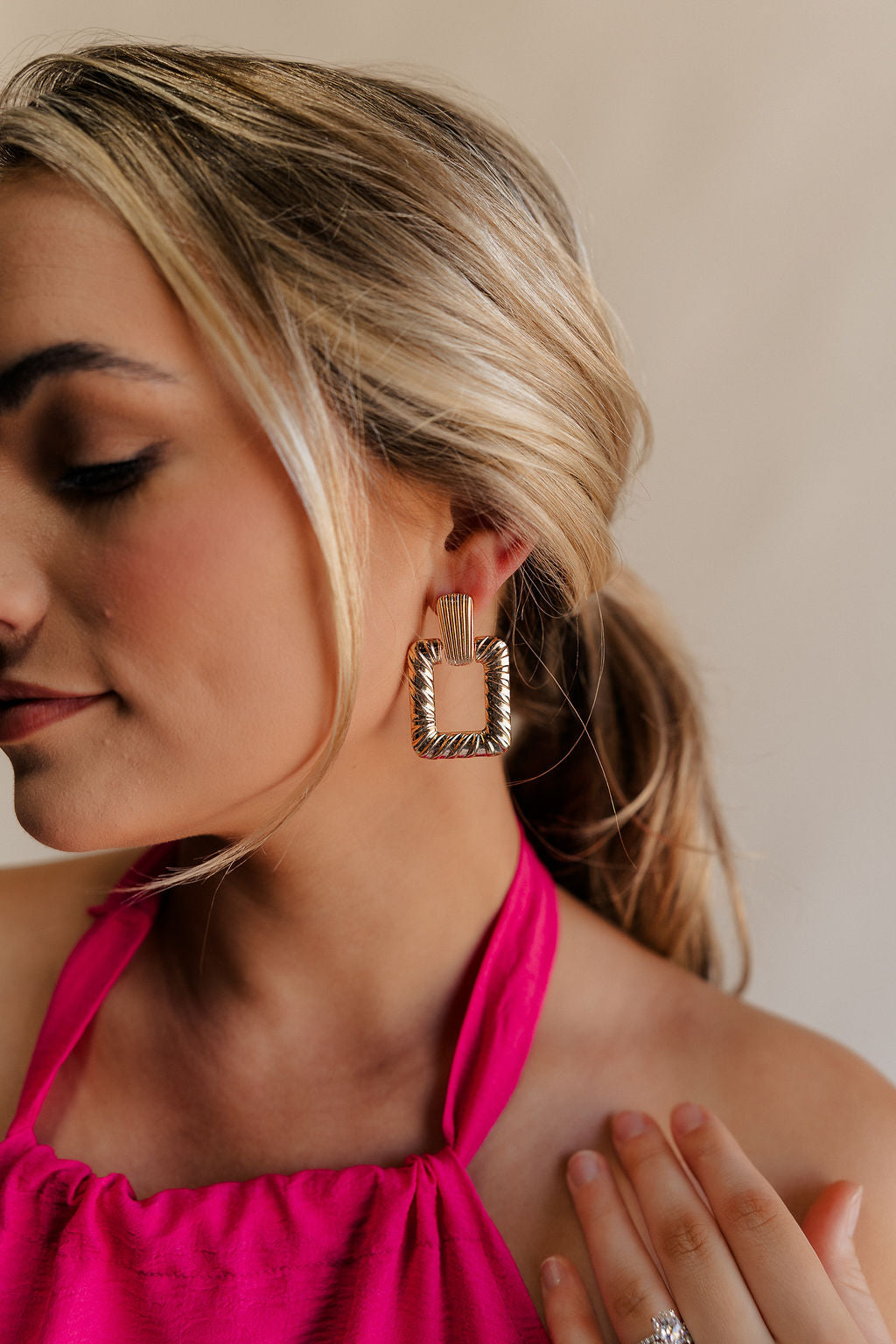 Side view of female model wearing the Ara Gold Square Dangle Earring which features gold roped details and open square shaped dangle earring