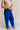 Side view of female model wearing the Freya Cobalt Blue Straight Leg Pants which features Cobalt Blue Cotton Fabric, Wide Pant Legs, Elastic Waistband and Two Side Pockets