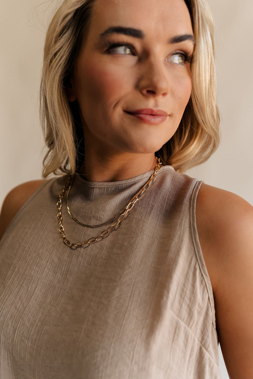Close up view of female model wearing the Annalise Gold Chain Layered Necklace which features one flat gold layer, gold chain layer and adjustable clasp closure
