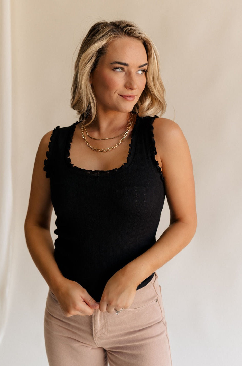 Front view of female model wearing the Myla Black Ruffle Sleeveless Tank which features Black Knit Fabric, Lettuce Hem Details, Round Neckline and Sleeveless