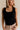 Close up front view of female model wearing the Myla Black Ruffle Sleeveless Tank which features Black Knit Fabric, Lettuce Hem Details, Round Neckline and Sleeveless