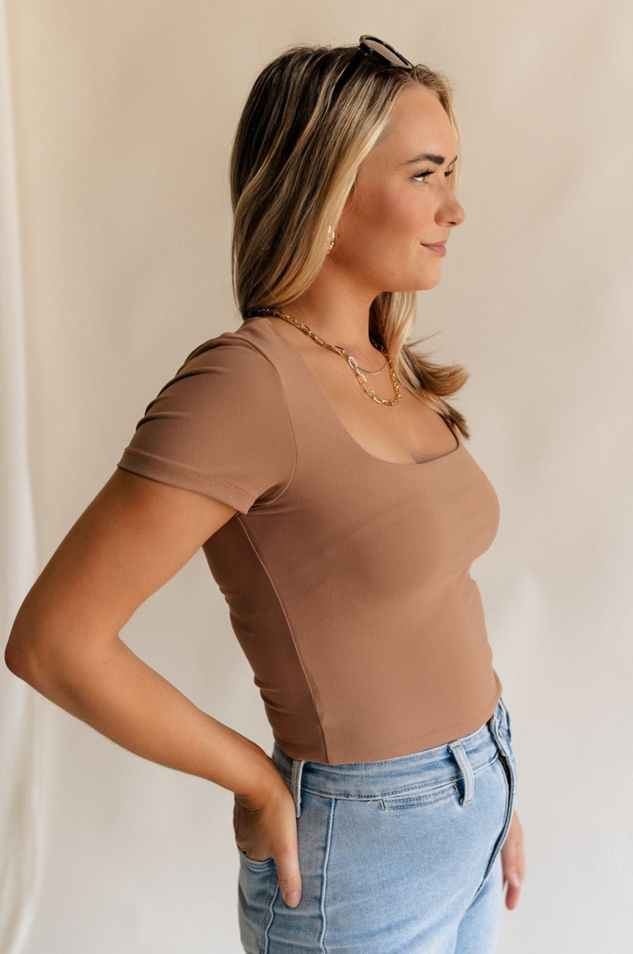 Side view of female model weariing the Saylor Toffee Brown Short Sleeve Top which features Light Brown Lightweight Fabric, Square Neckline and Short Sleeves
