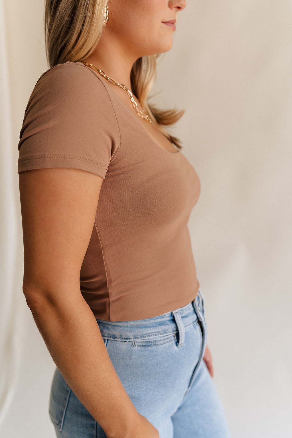 Close up side view of female model weariing the Saylor Toffee Brown Short Sleeve Top which features Light Brown Lightweight Fabric, Square Neckline and Short Sleeves