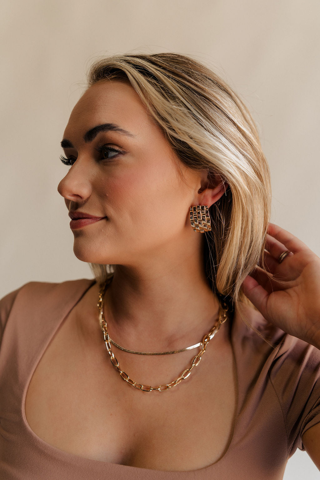 Side view of female model wearing the Eliana Gold Woven Stud Earring which features gold woven details, rectangle shaped stud with back closure