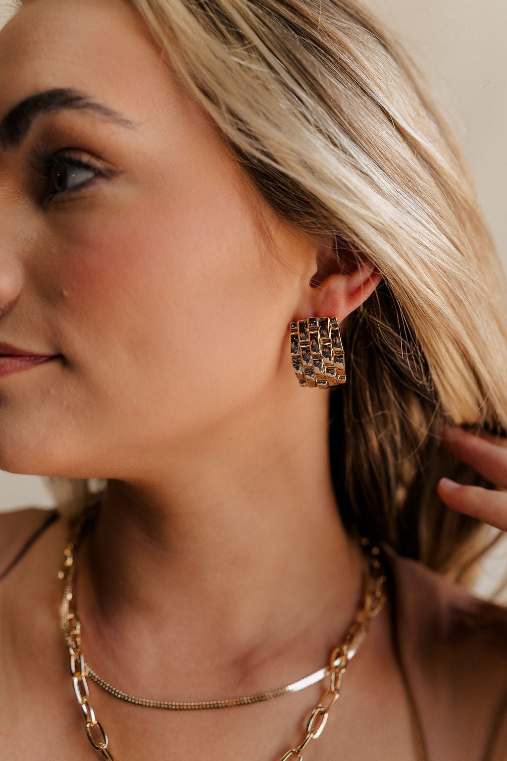 Close up view of female model wearing the Eliana Gold Woven Stud Earring which features gold woven details, rectangle shaped stud with back closure