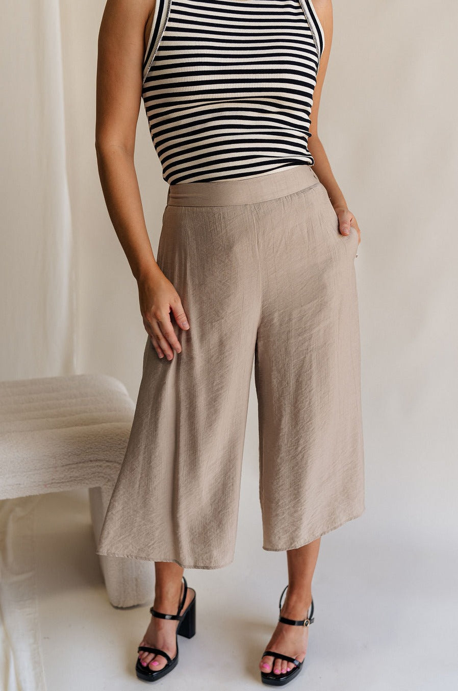 Front view of female model wearing the Sienna Light Taupe Cropped Flare Pants which features Lightweight Taupe Fabric, Taupe Lining, Cropped Wide Pant Legs, Pockets on each side and Back Elastic Waistband