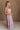 Full body side view of female model wearing the Imani Lavender Maxi Dress that has lavender fabric, thin straps, and a ruffled maxi hem.