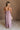 Full body back view of female model wearing the Imani Lavender Maxi Dress that has lavender fabric, thin straps, and a ruffled maxi hem.