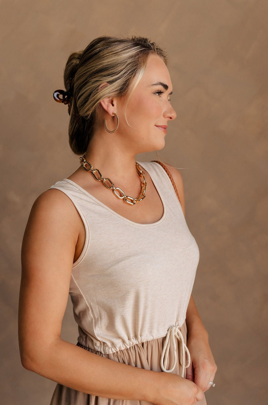 Side view of female model wearing the Celeste Gold Chain Link Necklace which features shiny gold, chunky chain links linked together with an adjustable clasp closure.