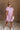 Full body front view of female model wearing the Cameron Pink & White Striped Dress that has pink and white vertical striped fabric, short puff sleeves, a tiered skirt, and button up front.