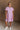 Full body front view of female model wearing the Cameron Pink & White Striped Dress that has pink and white vertical striped fabric, short puff sleeves, a tiered skirt, and button up front.