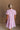 Upper body back view of female model wearing the Cameron Pink & White Striped Dress that has pink and white vertical striped fabric, short puff sleeves, a tiered skirt, and button up front.