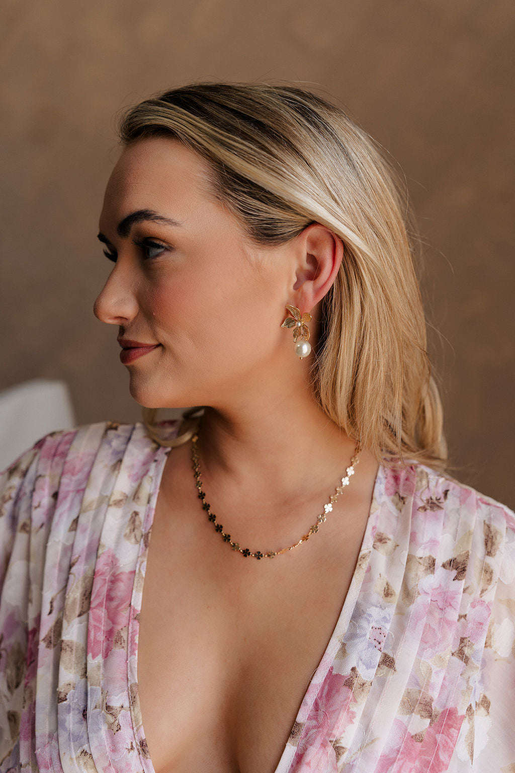 Side view of female model wearing the Angelica Gold Clover Necklace which features gold mini clovers linked together with an adjustable clasp closure