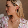 Side view of female model wearing the Angelica Gold Clover Necklace which features gold mini clovers linked together with an adjustable clasp closure