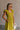 Upper body side view of female model wearing the Kristina Chartreuse Smocked Sleeveless Midi Dress that has chartreuse fabric with a smocked upper, ruffle straps, and a midi length hem.