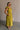 Upper body side view of female model wearing the Kristina Chartreuse Smocked Sleeveless Midi Dress that has chartreuse fabric with a smocked upper, ruffle straps, and a midi length hem.