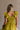Upper body back view of female model wearing the Kristina Chartreuse Smocked Sleeveless Midi Dress that has chartreuse fabric with a smocked upper, ruffle straps, and a midi length hem.